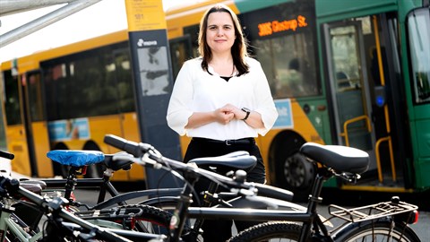 Woman is standing surrounded by bikes in front of a city bus. Photo: Bax Lindhardt