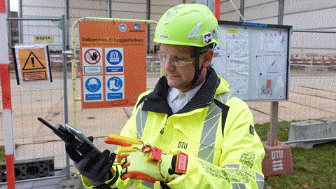 Man in a high vis jacket and hard hat by a construction site. Photo: Olga Golovina